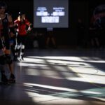 Bundesliga 2026: Ausschreibung und Regeländerungen Auf dem Track stehen im Schatten mehrere Roller Derby Spieler:innen. Im Hintergrund steht das Scoreboard.
